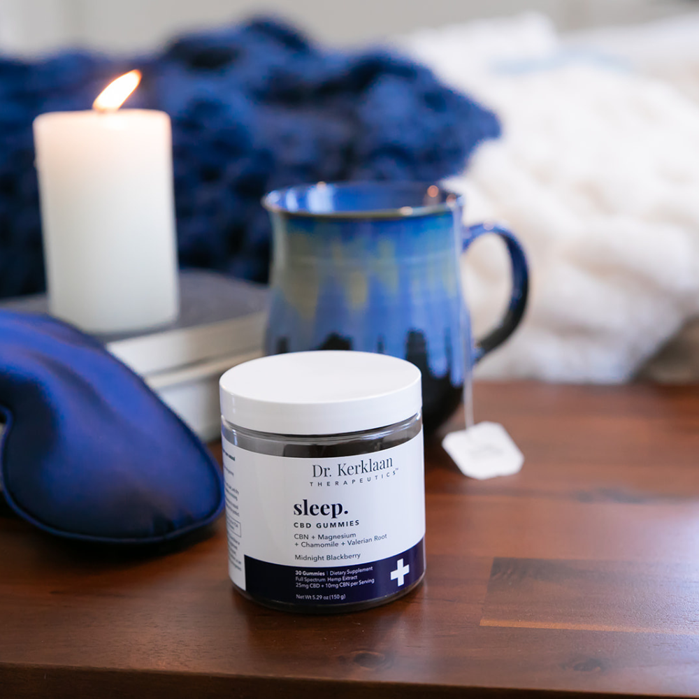 Dr. Kerklaan Sleep CBD Gummies on a nightstand with candlelight, tea, and a sleep mask—designed to support restful sleep and nighttime relaxation.