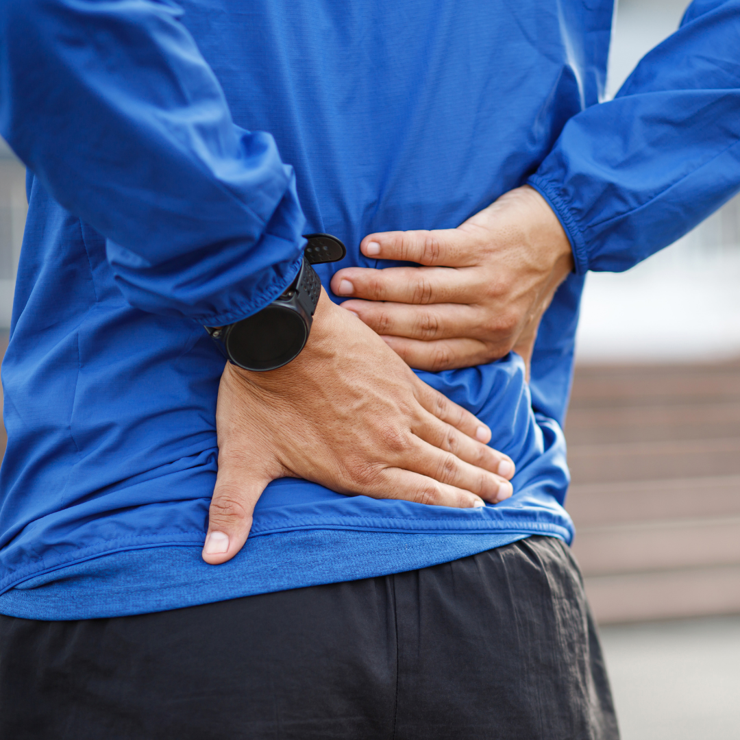 Close-up of a man in a blue sports jacket holding his lower back in pain, highlighting back discomfort and potential relief with a CBD stick