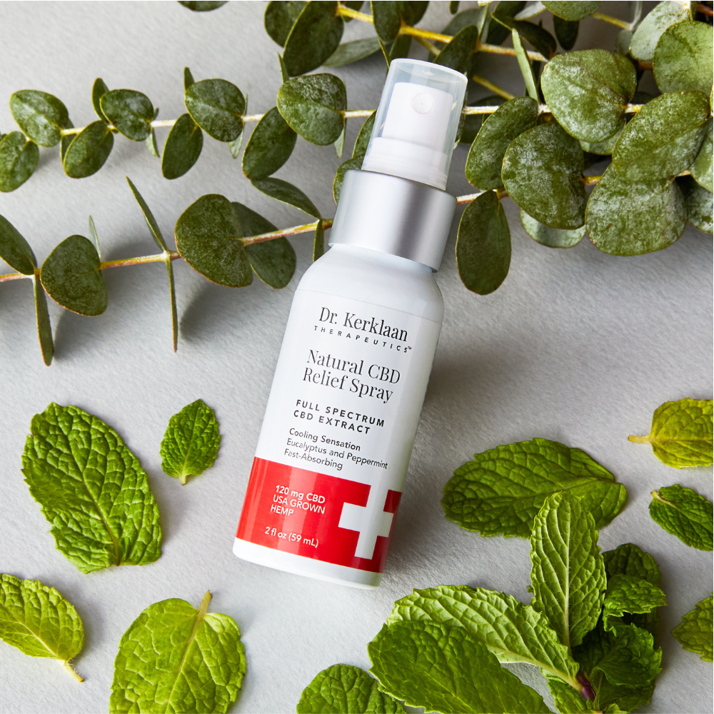 Dr. Kerklaan Natural CBD Relief Spray placed with fresh eucalyptus and peppermint leaves for a natural touch.